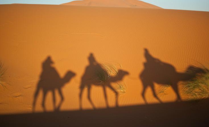 Silhouette of three men on camels
